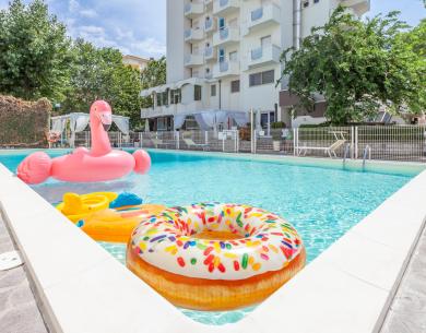 Piscina con gonfiabili colorati e un edificio sullo sfondo.