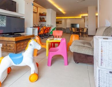 Stanza colorata per bambini con giochi, sedie vivaci e passeggini, atmosfera accogliente.