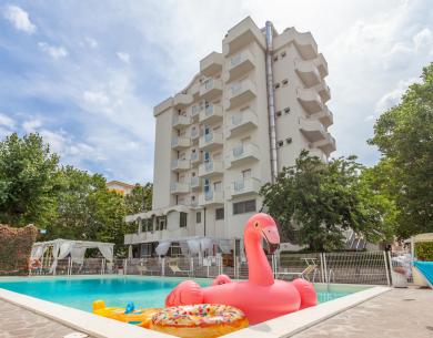 Piscina con fenicottero gonfiabile davanti a un hotel.