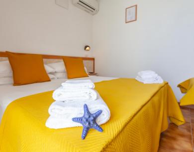 Camera accogliente con letto matrimoniale, cuscini gialli e stella marina decorativa.