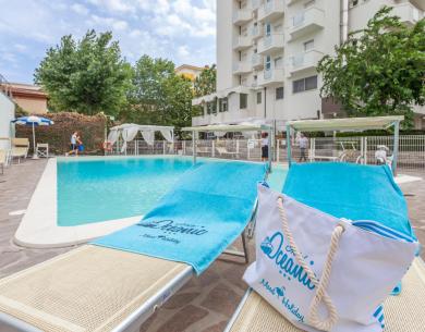 Piscina tranquilla con lettini e teli azzurri, atmosfera rilassante e vacanziera.