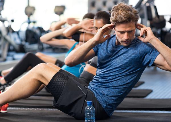 Personen machen Bauchübungen im Fitnessstudio.