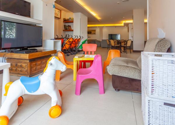 Stanza colorata per bambini con giochi, sedie vivaci e passeggini, atmosfera accogliente.