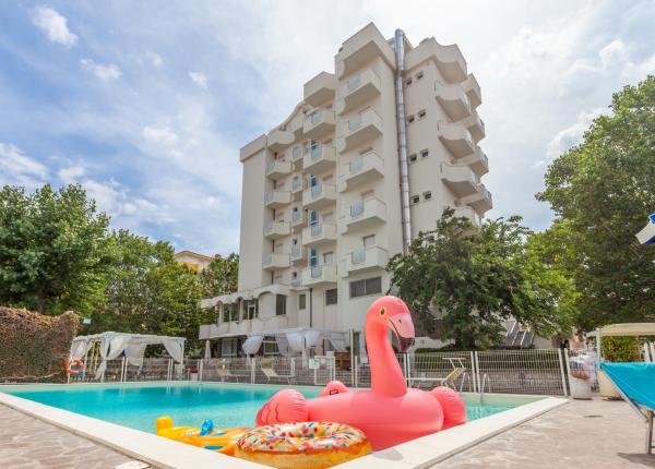 Piscina con fenicottero gonfiabile davanti a un hotel.